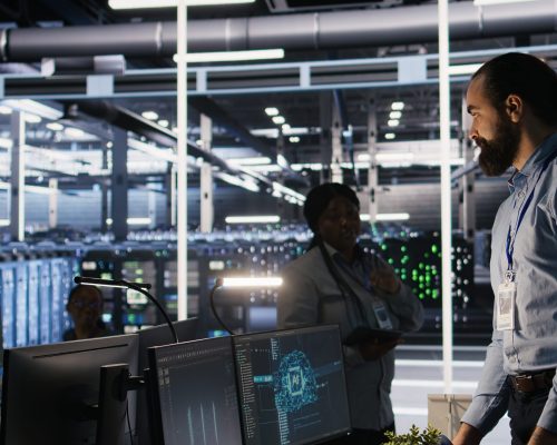 Upset data center worker packing personal items at workstation after being replaced by AI. Programmer removing belongings from server hub workplace desk, fired by artificial intelligence, camera A